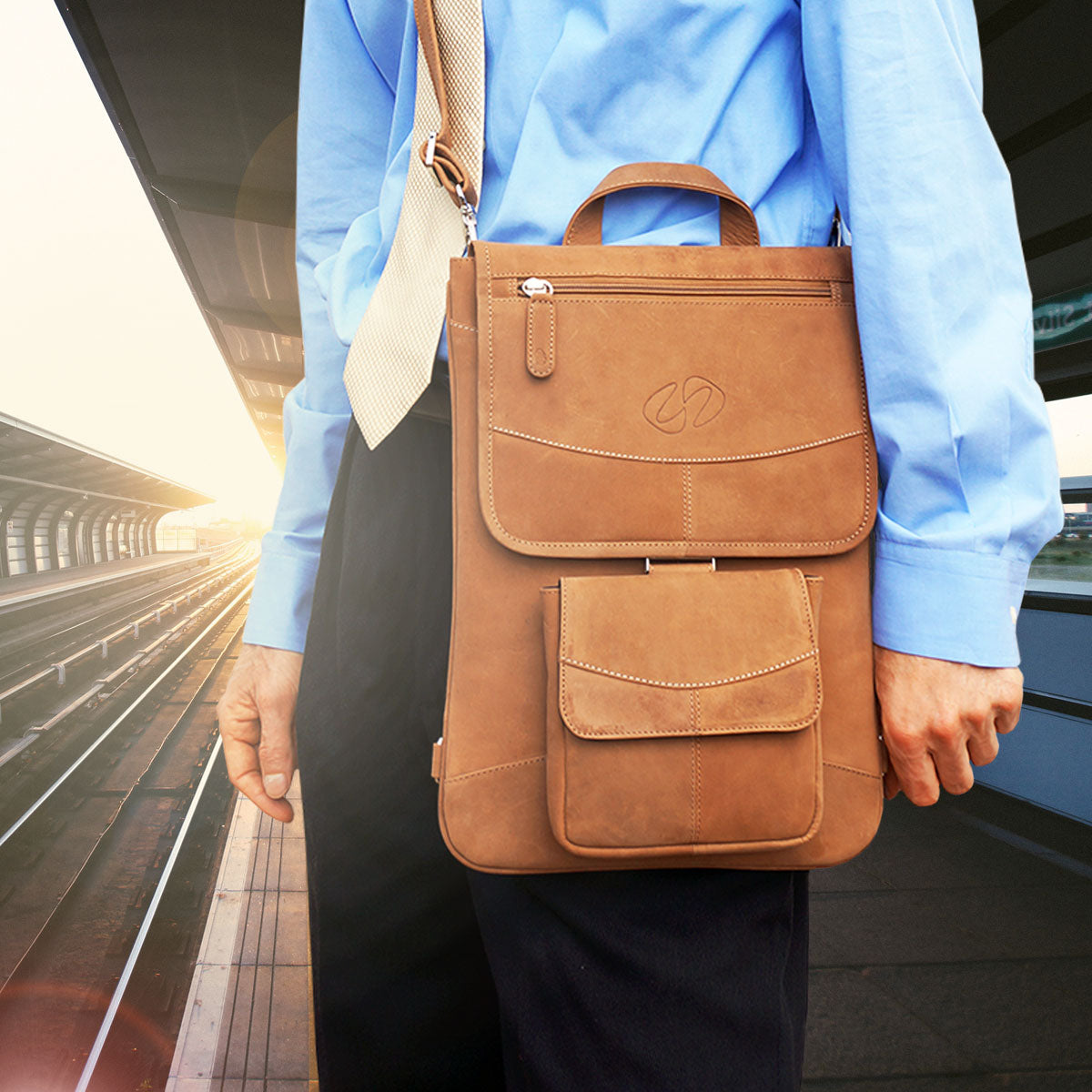 Person holding a brown leather backpack on a train platform