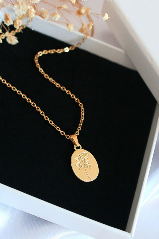 Gold necklace with a pendant on a black cushion in a white box