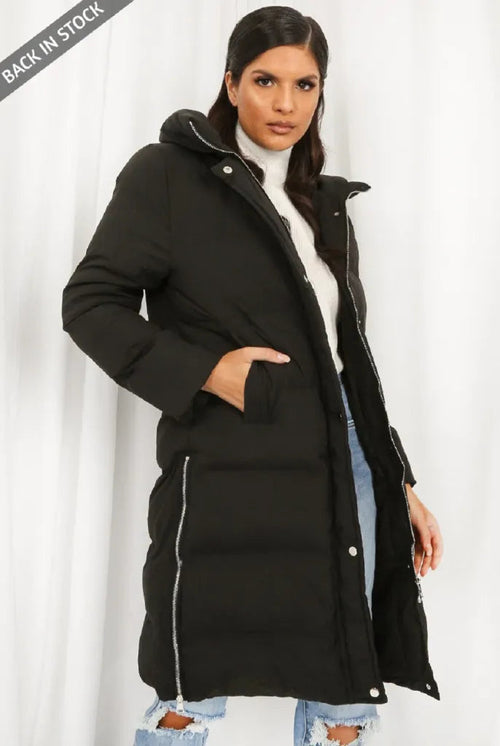 Woman wearing a black puffer coat against a white background
