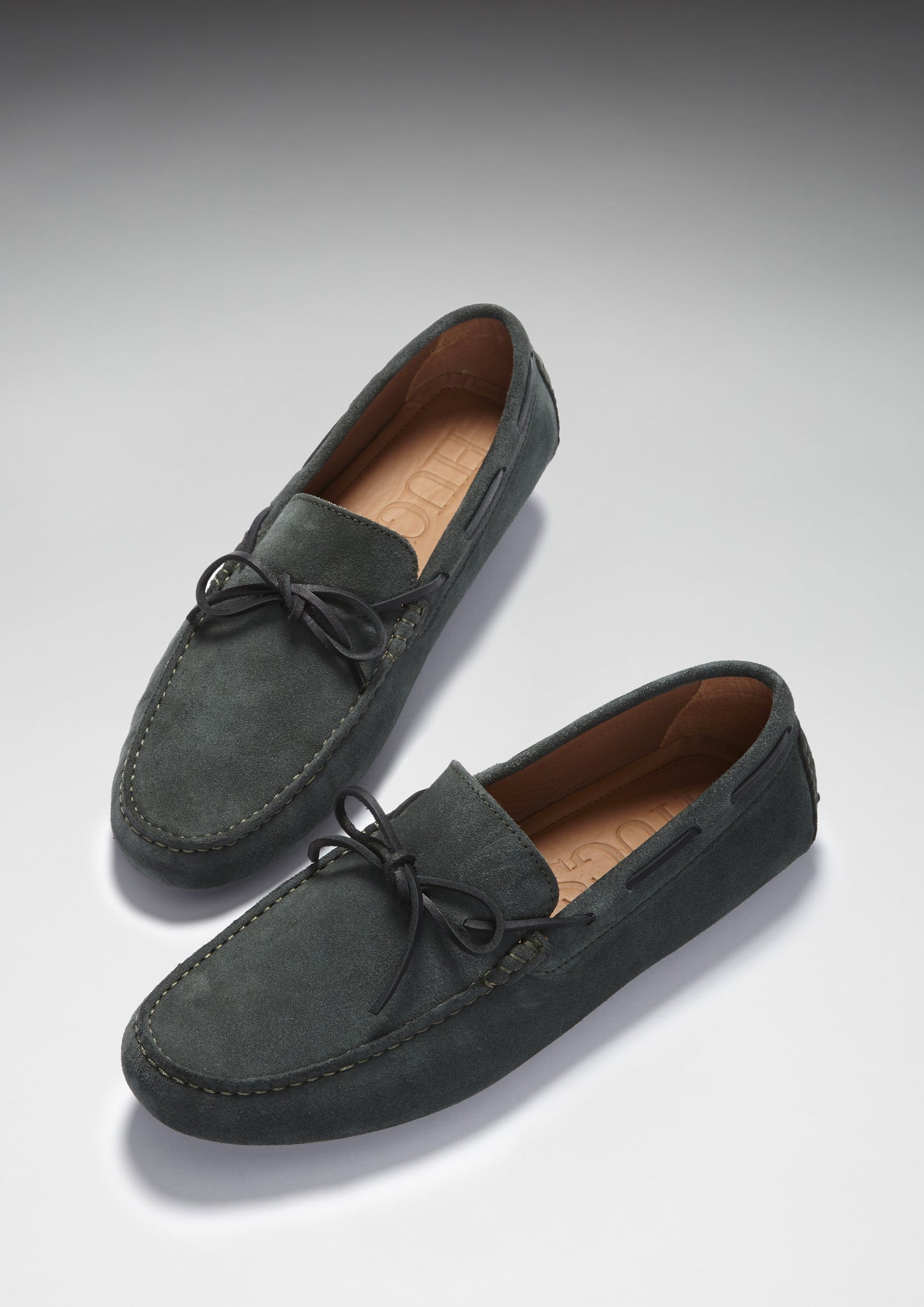 Pair of dark gray suede loafers on a light gray background