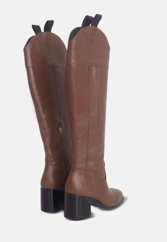 Brown riding boots with black soles on a white background