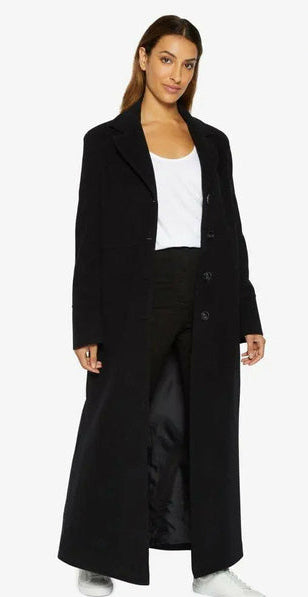 Woman wearing a long black coat with a white background