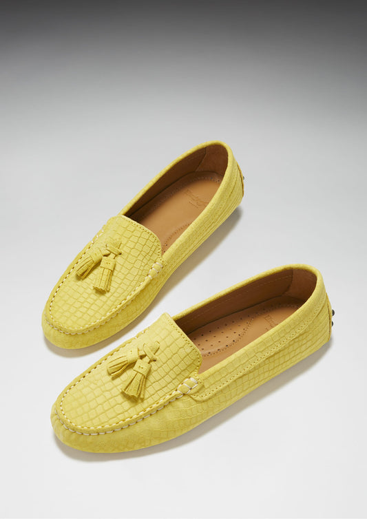 Pair of yellow loafers with tassels on a gray background