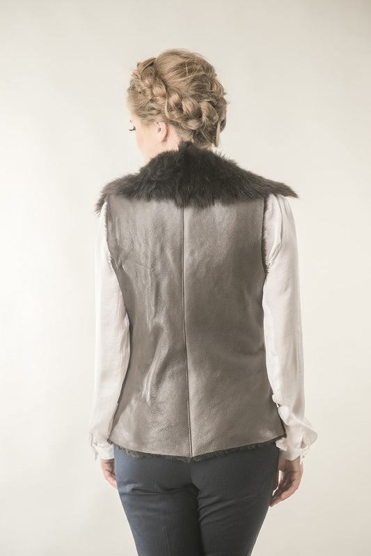 Person wearing a gray leather vest with fur collar on a plain background