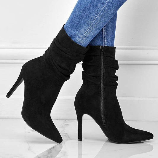 Black high-heeled boots worn with blue jeans on a light background
