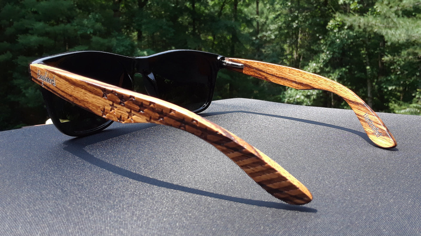 Wooden-framed sunglasses on a car hood with a blurred natural background