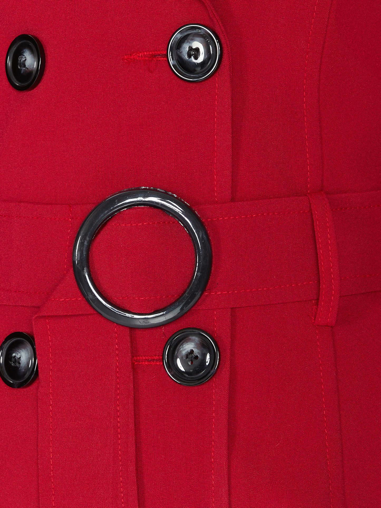Close-up of a red coat with black buttons and a ring detail.