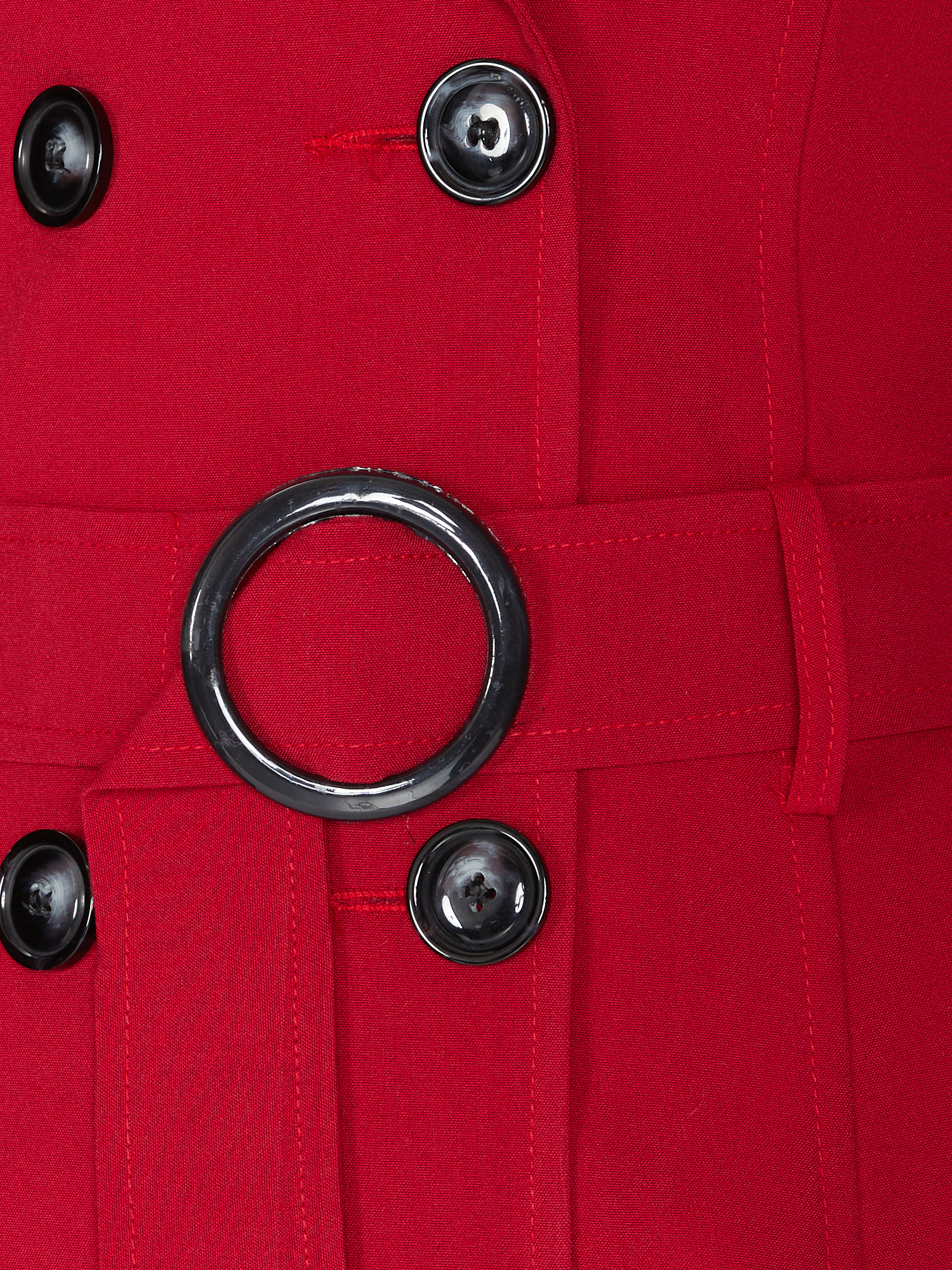 Close-up of a red coat with black buttons and a ring detail.