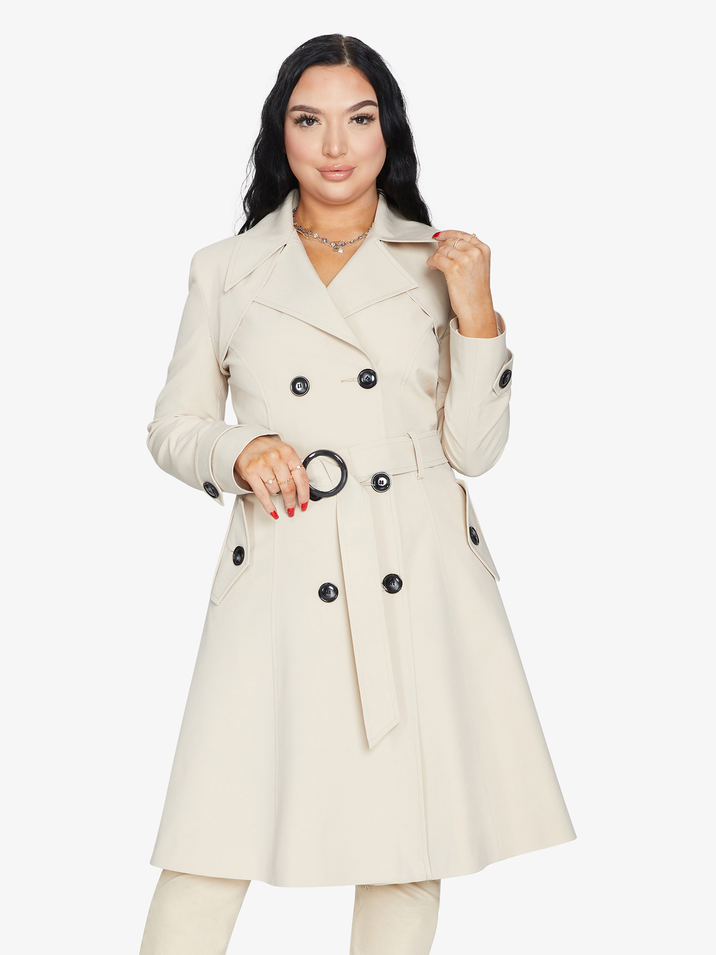 Woman wearing a beige trench coat with black buttons on a white background