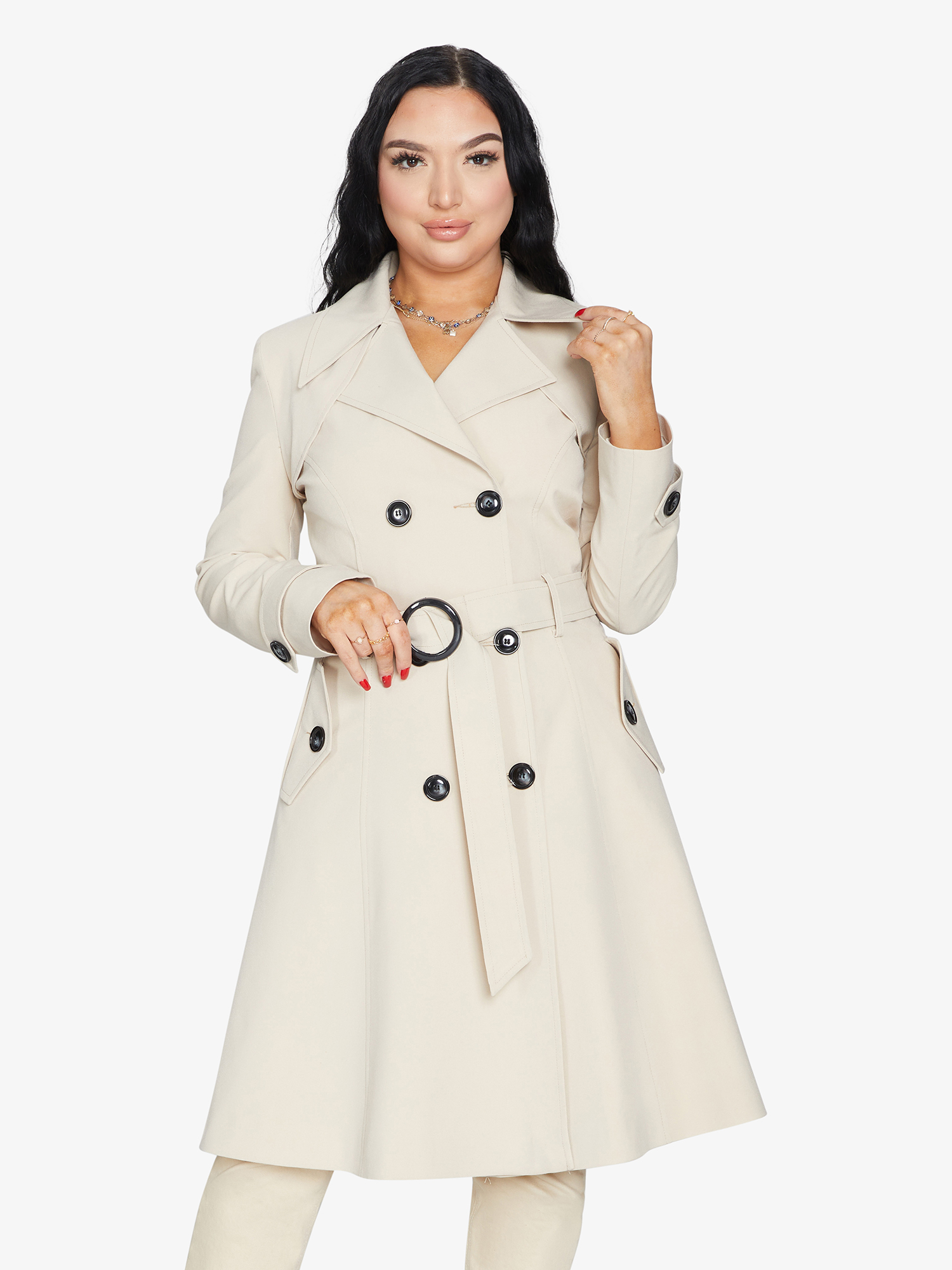 Woman wearing a beige trench coat with black buttons on a white background