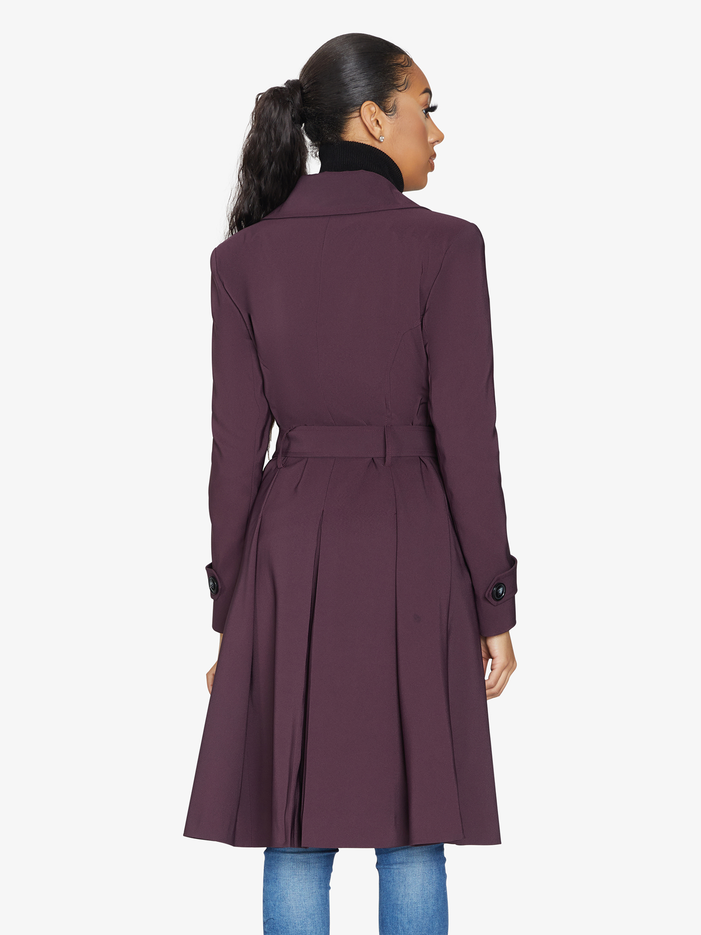 Woman wearing a long purple coat on a white background