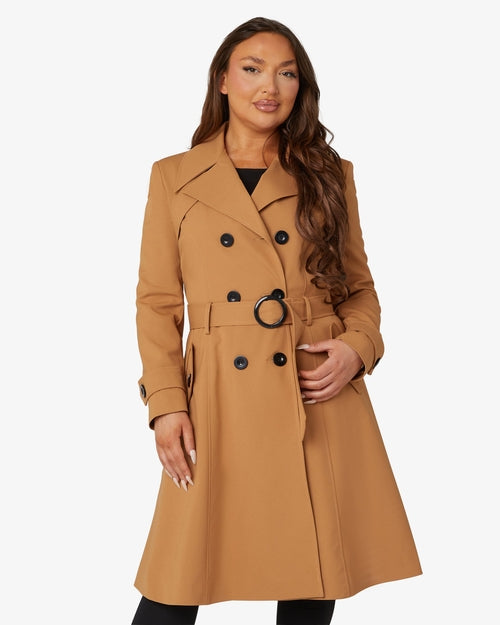 Woman wearing a tan trench coat on a white background