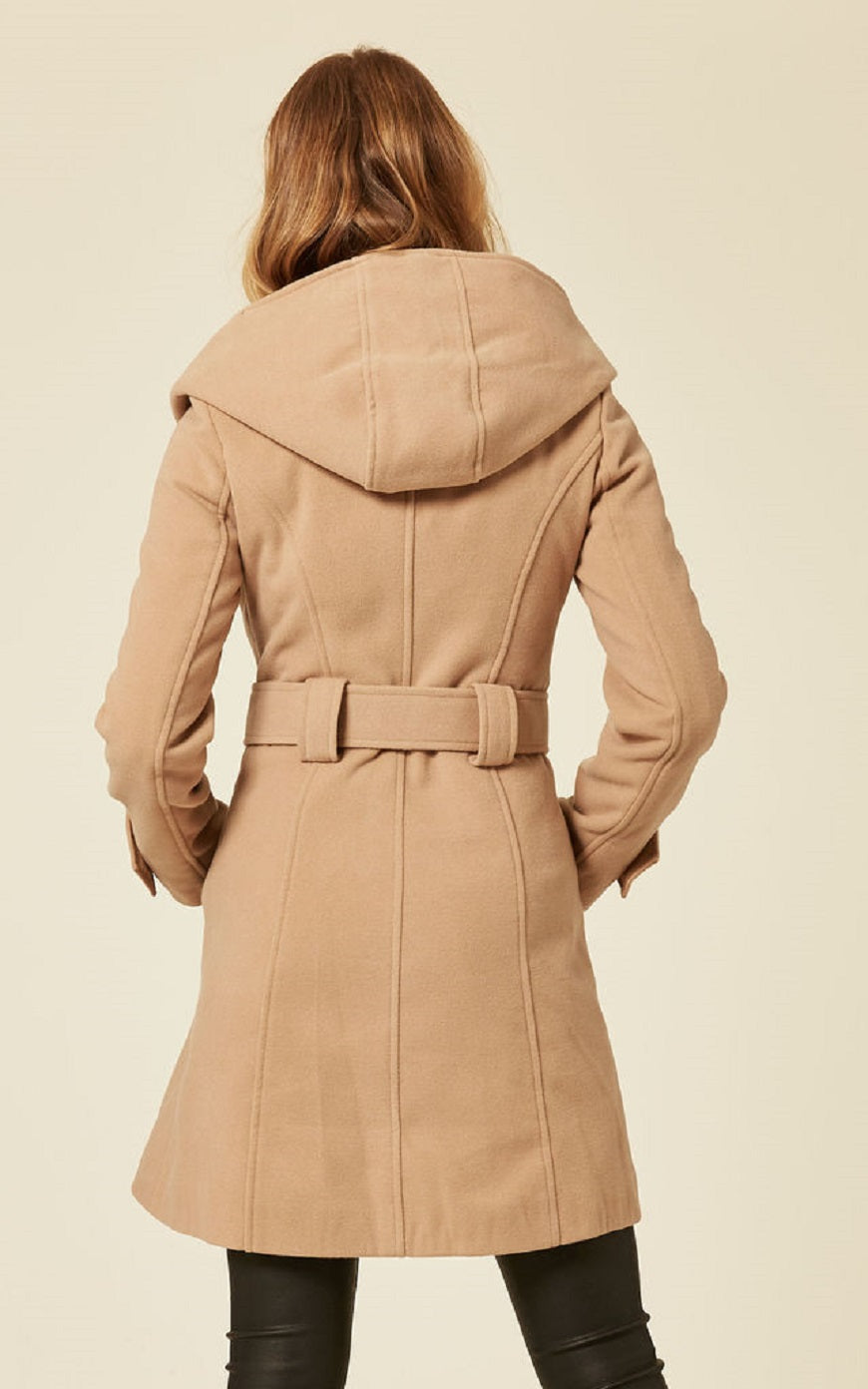 Woman wearing a beige coat with a hood on a beige background