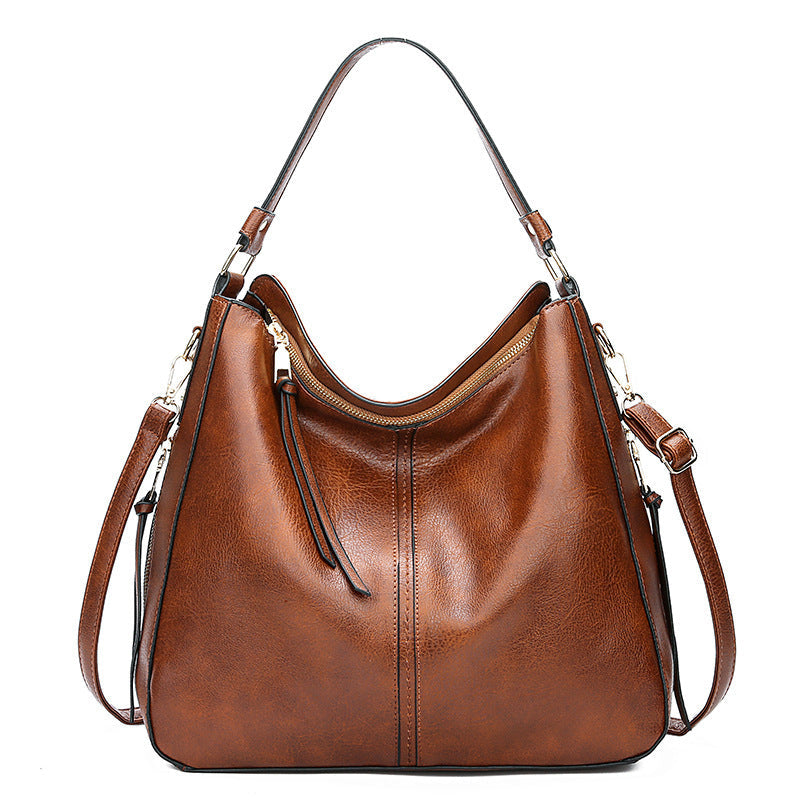 Brown leather handbag with shoulder straps on a white background