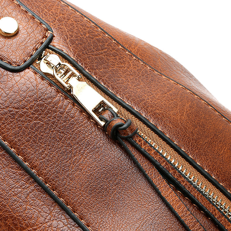 Close-up of a brown leather bag with a gold zipper and visible brand logo.