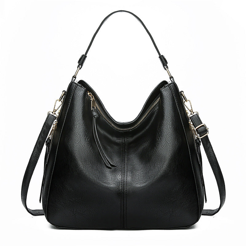 Black leather handbag with gold zippers on a white background