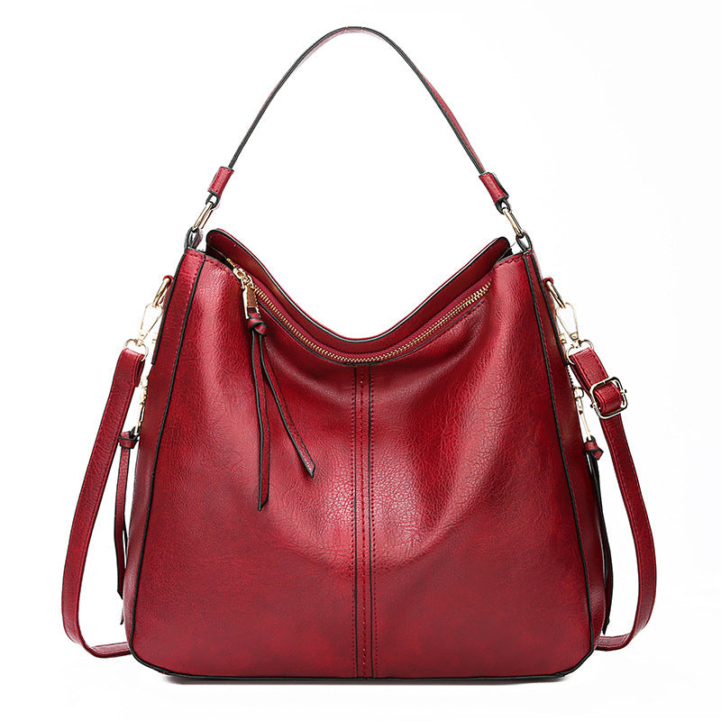 Red leather handbag with gold accents on a white background