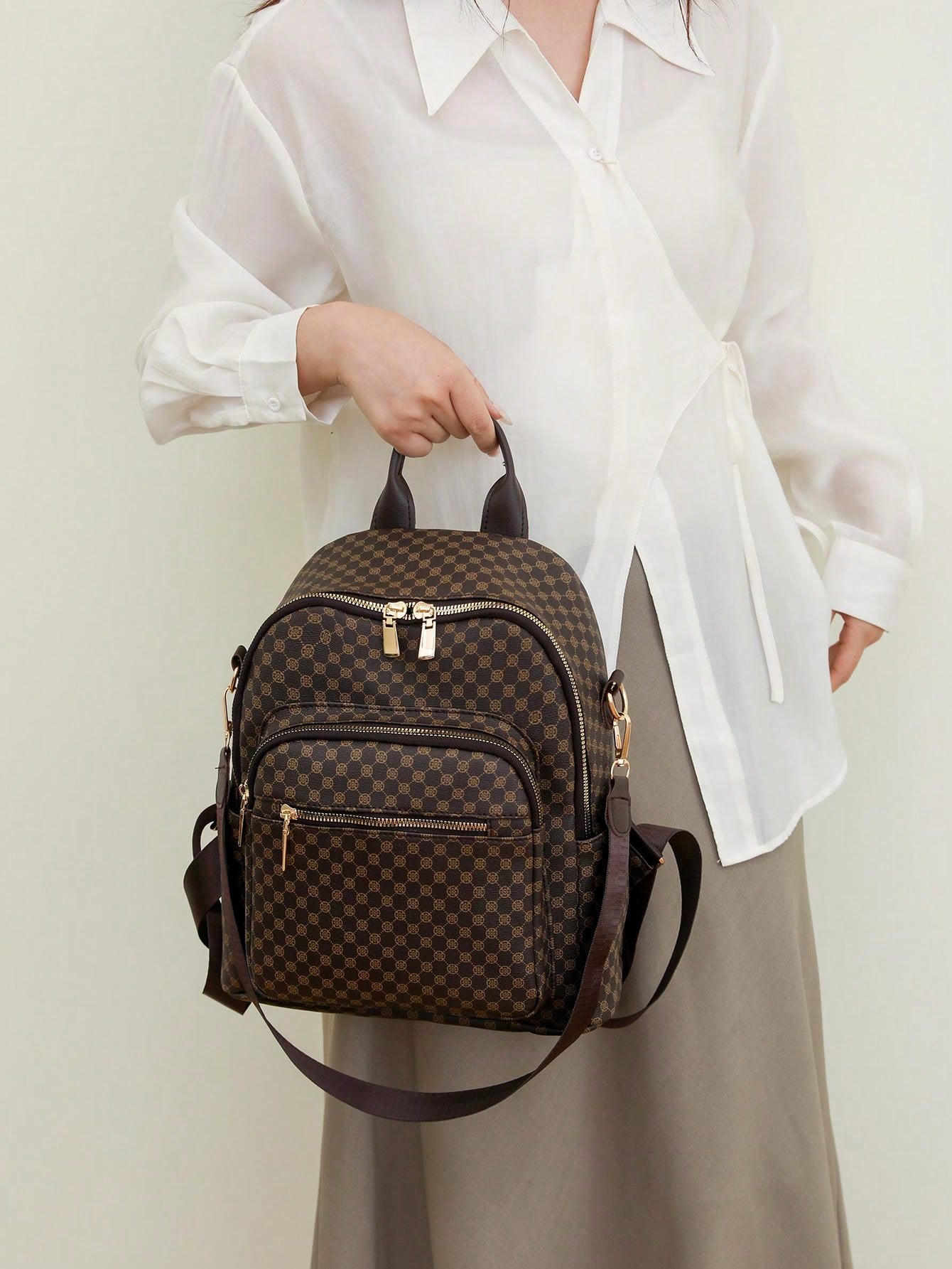Person holding a brown checkered backpack against a light background