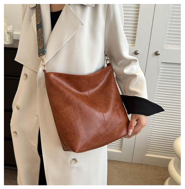Person holding a brown leather handbag in an indoor setting