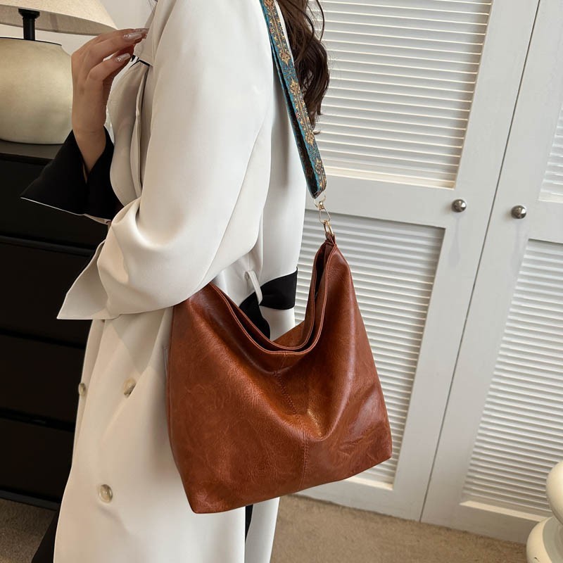Person holding a brown leather handbag with a white background