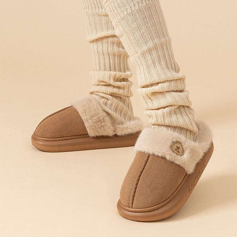 Beige slippers with fluffy trim worn with cream socks on a beige background