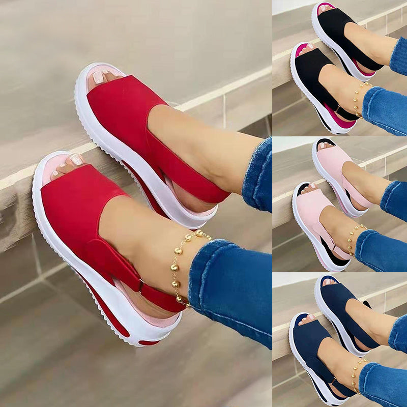 Red platform sandals worn with blue jeans on a neutral background