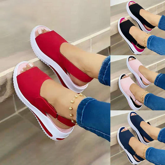 Red platform sandals worn with blue jeans on a neutral background