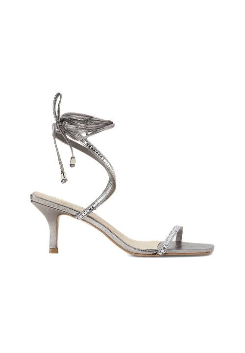 Silver high-heeled sandal with intricate design on a white background