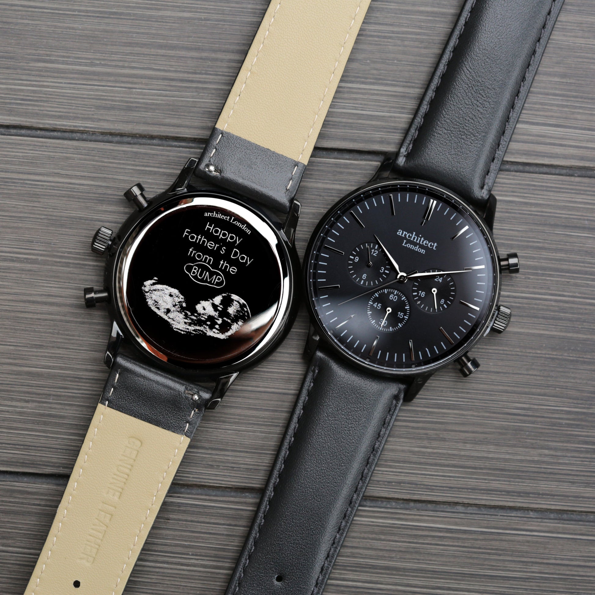 Two watches with black faces and leather straps on a wooden surface