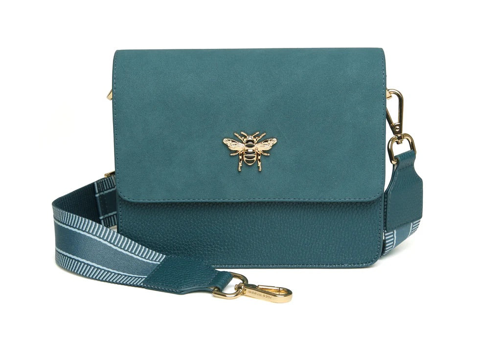 Teal handbag with bee emblem and striped strap on a white background