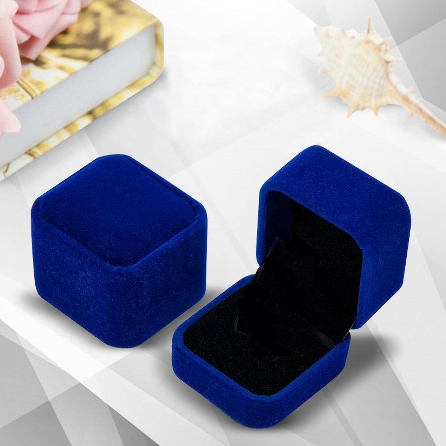 Two blue velvet jewelry boxes on a white surface with a blurred background
