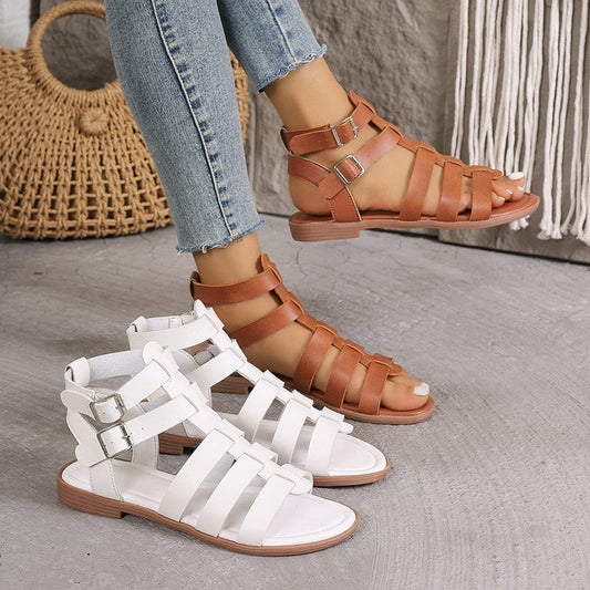 Brown and white strappy sandals on a neutral background