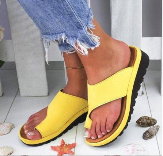 Yellow sandals worn with denim shorts on a light background