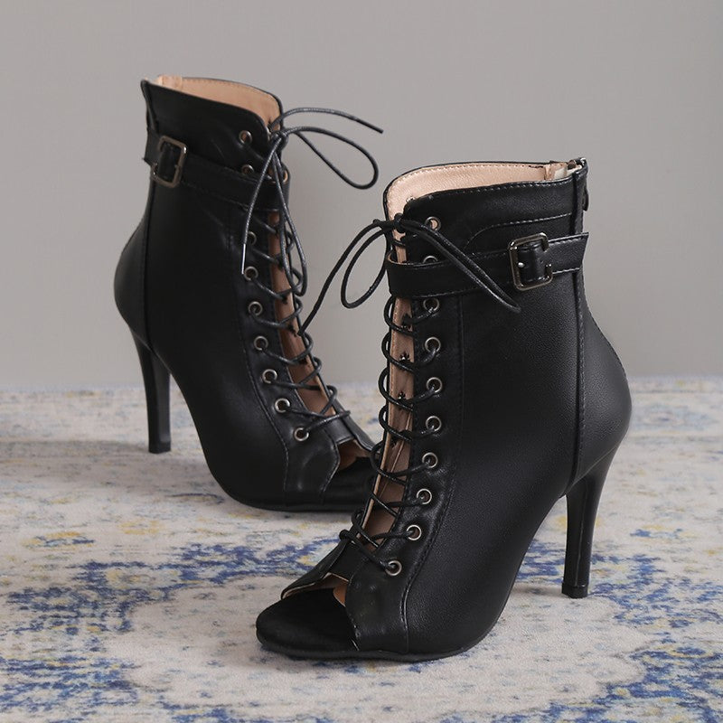 Black lace-up high-heeled boots on a textured surface with a neutral background