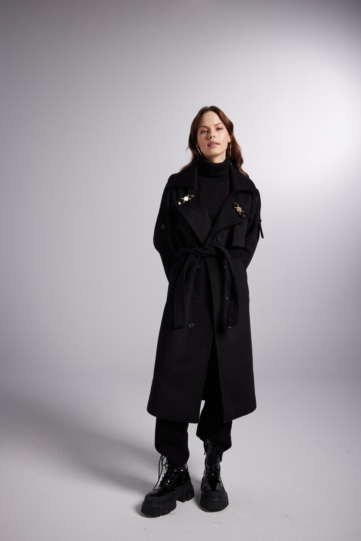 Person wearing a black coat on a gray background