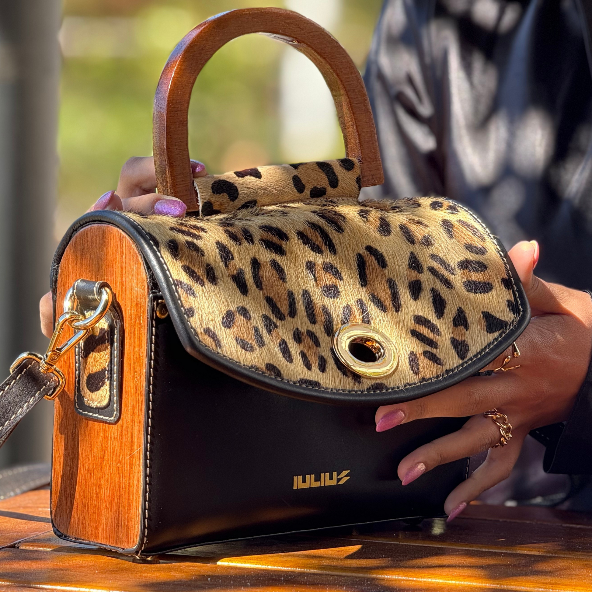 Leopard print handbag with wooden accents held by a person.