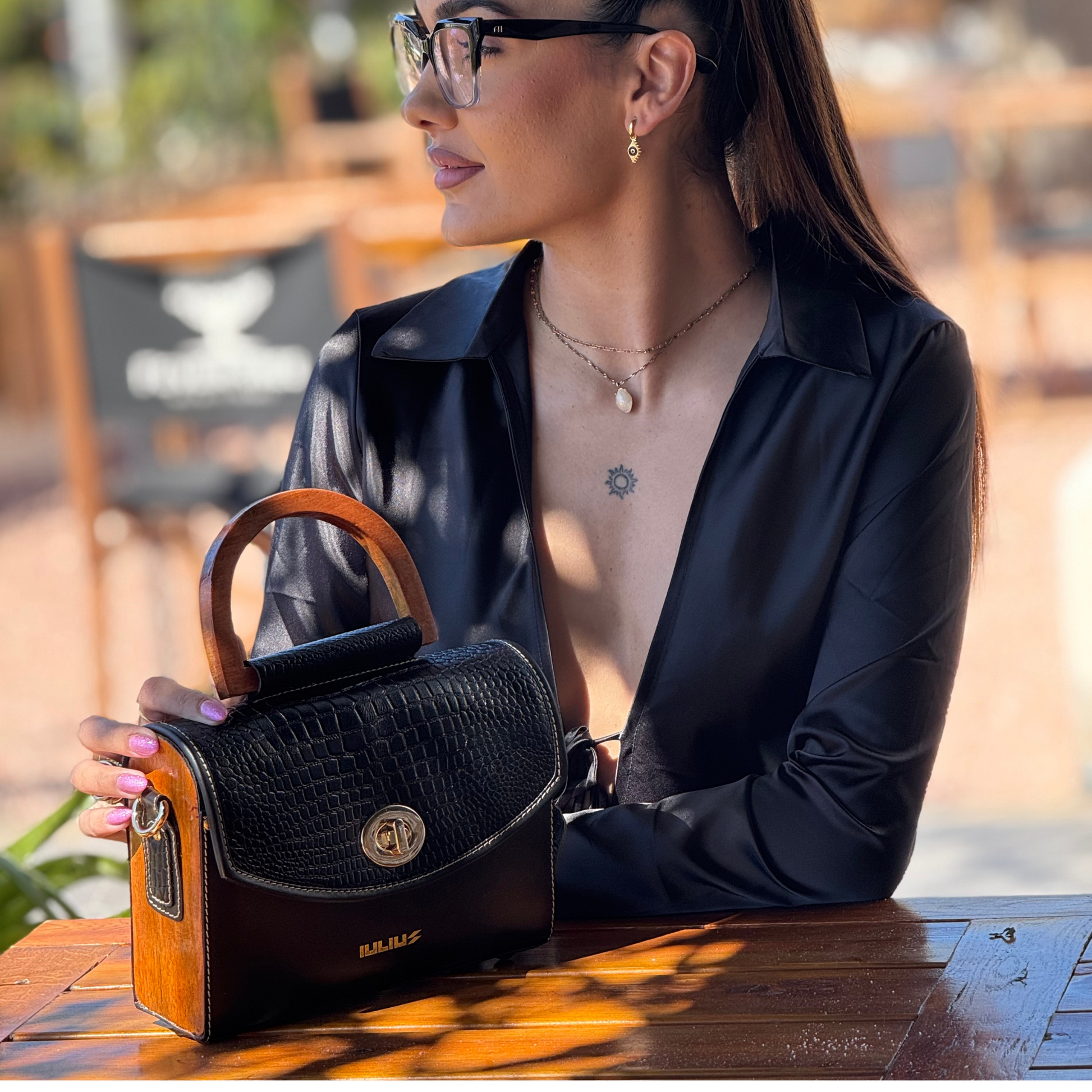 Woman holding a black handbag with wooden handle outdoors