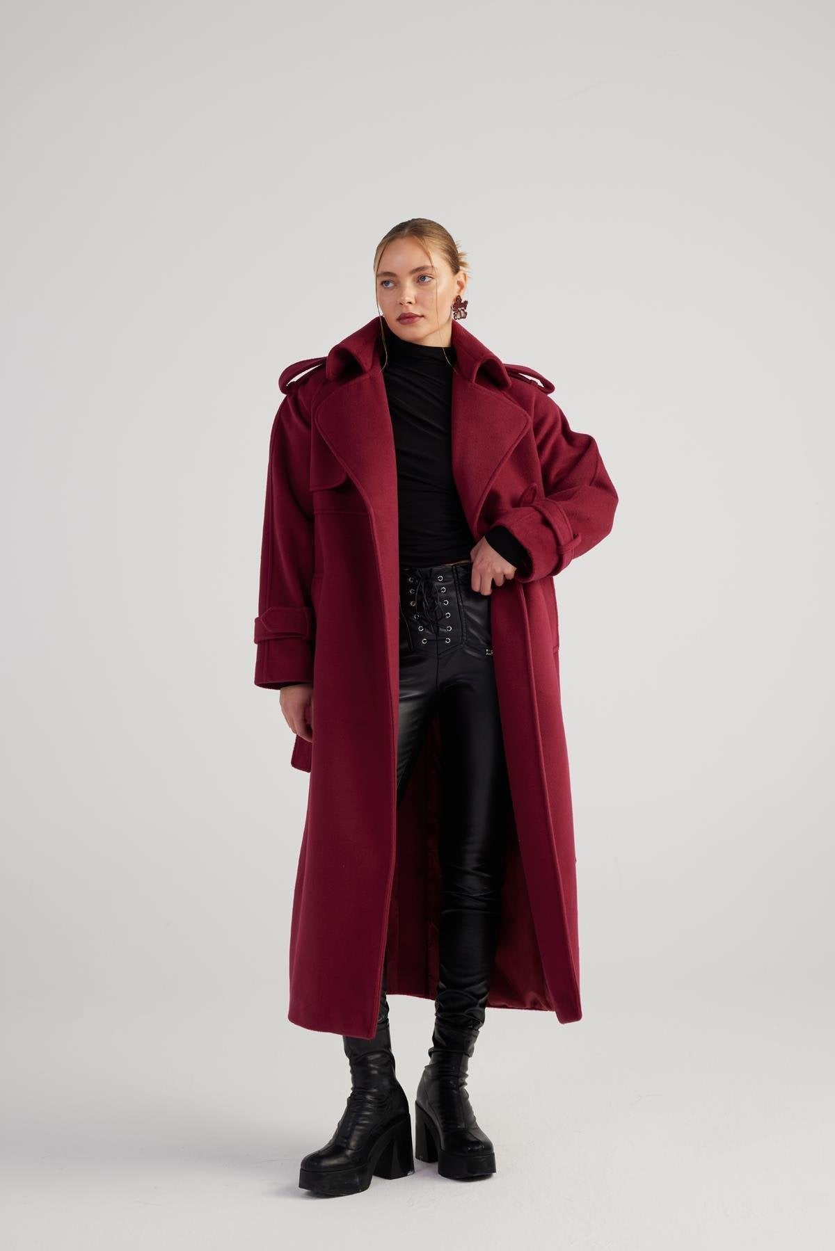 Person wearing a long burgundy coat on a plain background