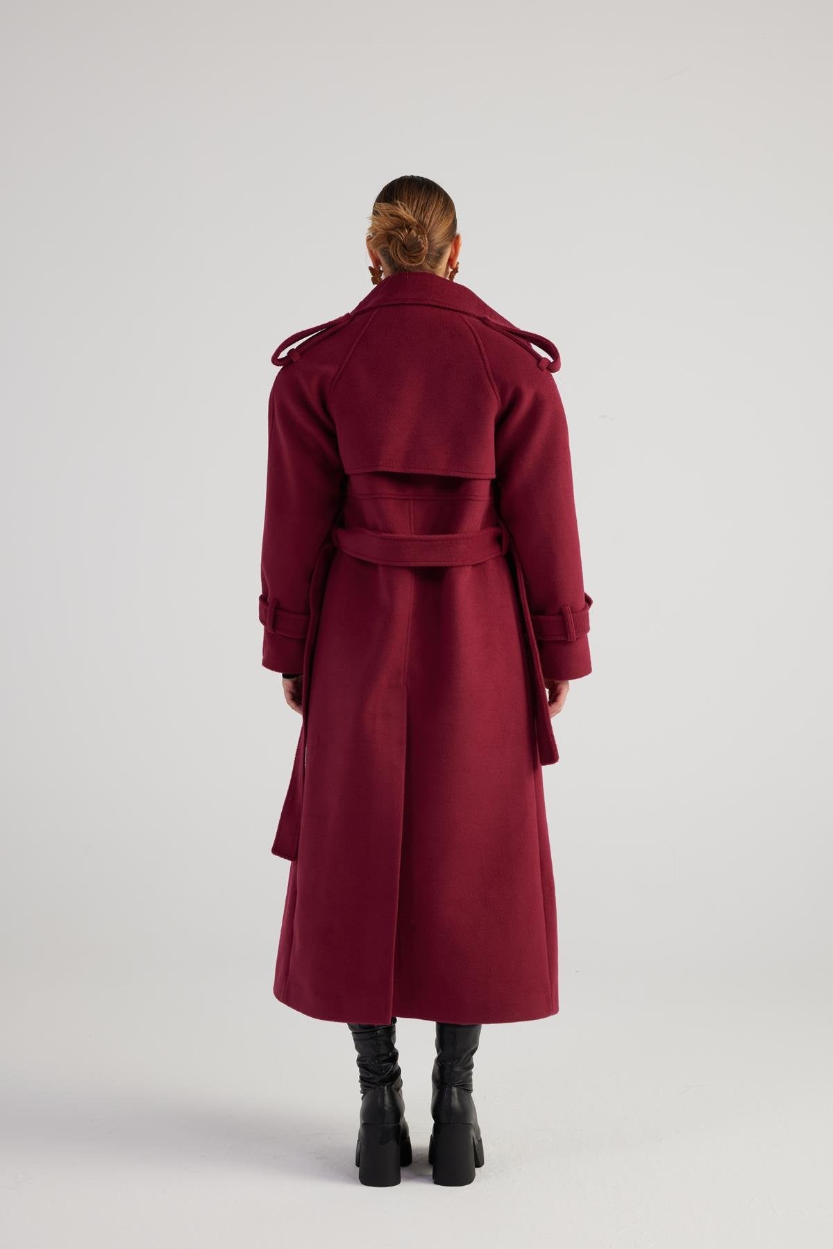 Person wearing a burgundy coat from behind on a white background