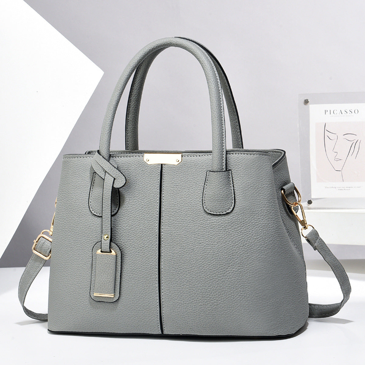 Gray handbag with gold accents on a light gray background
