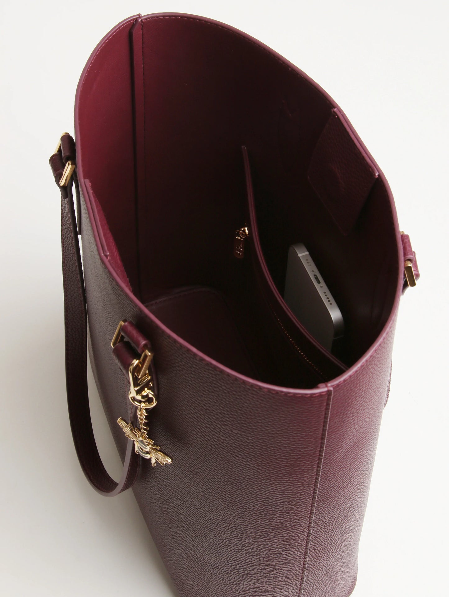 Close-up of a burgundy handbag with gold accents on a white background