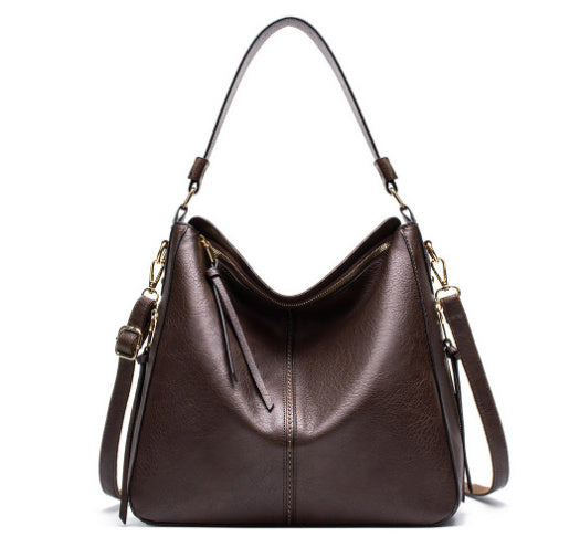 Brown leather handbag with gold accents on a white background