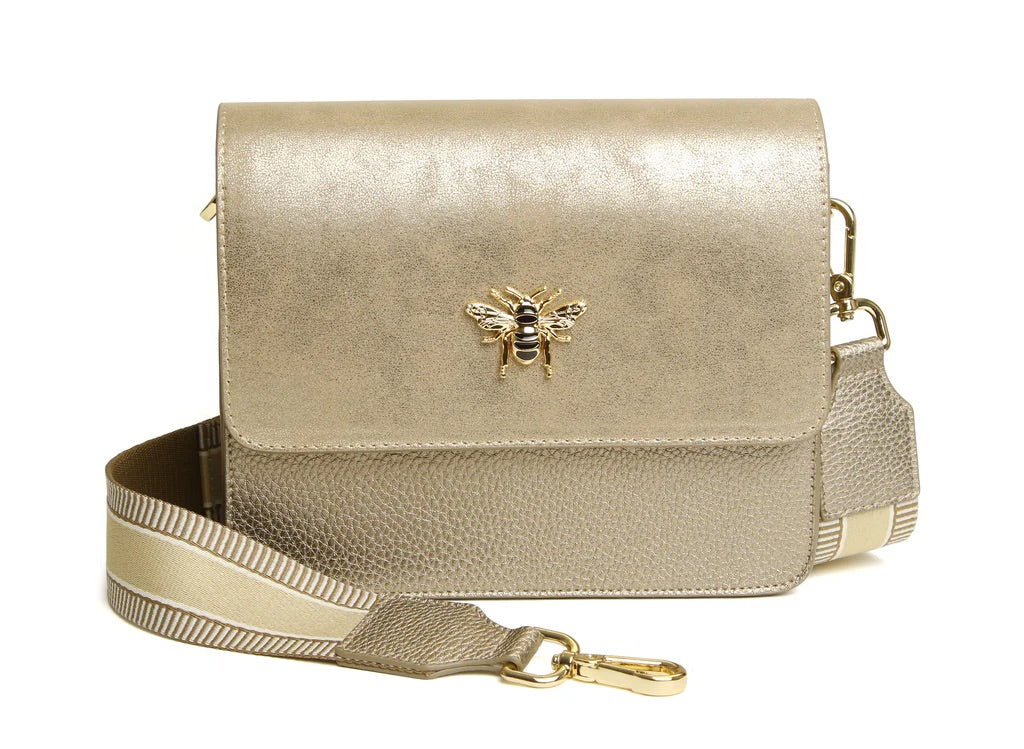 Gold metallic handbag with a bee emblem on a white background