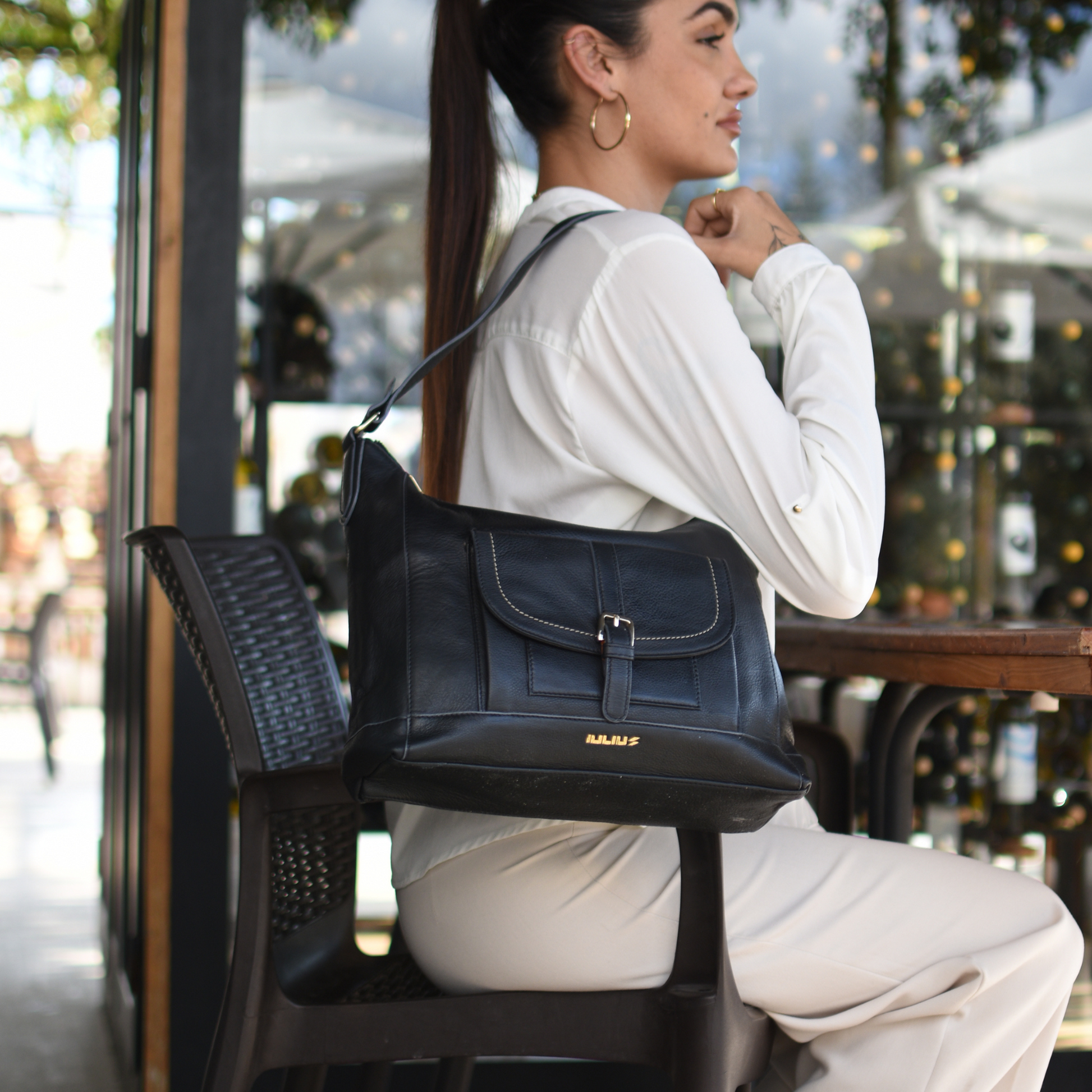 Woman sitting outdoors with a black handbag on her lap