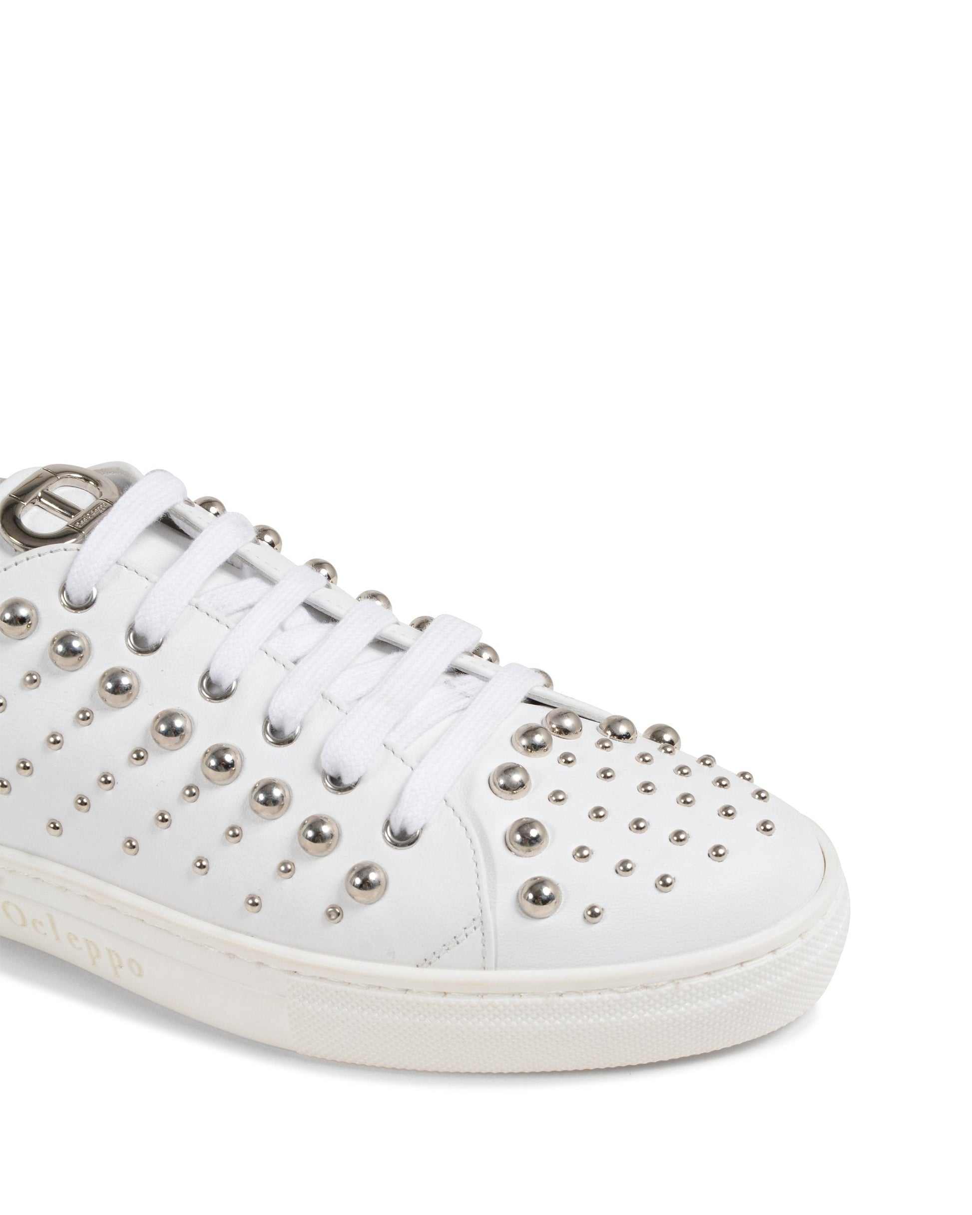 White sneaker with silver studs on a white background