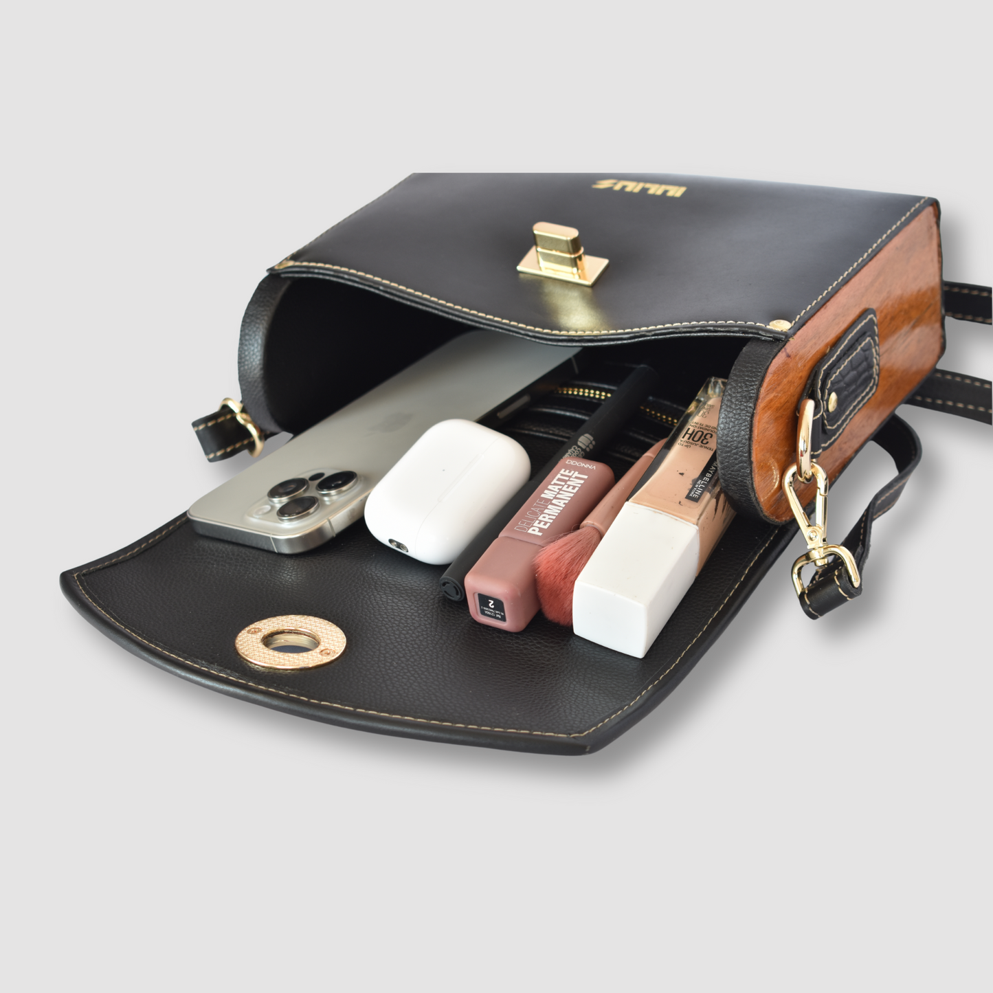 Black and brown leather pouch with gold accents containing electronic devices on a light gray background