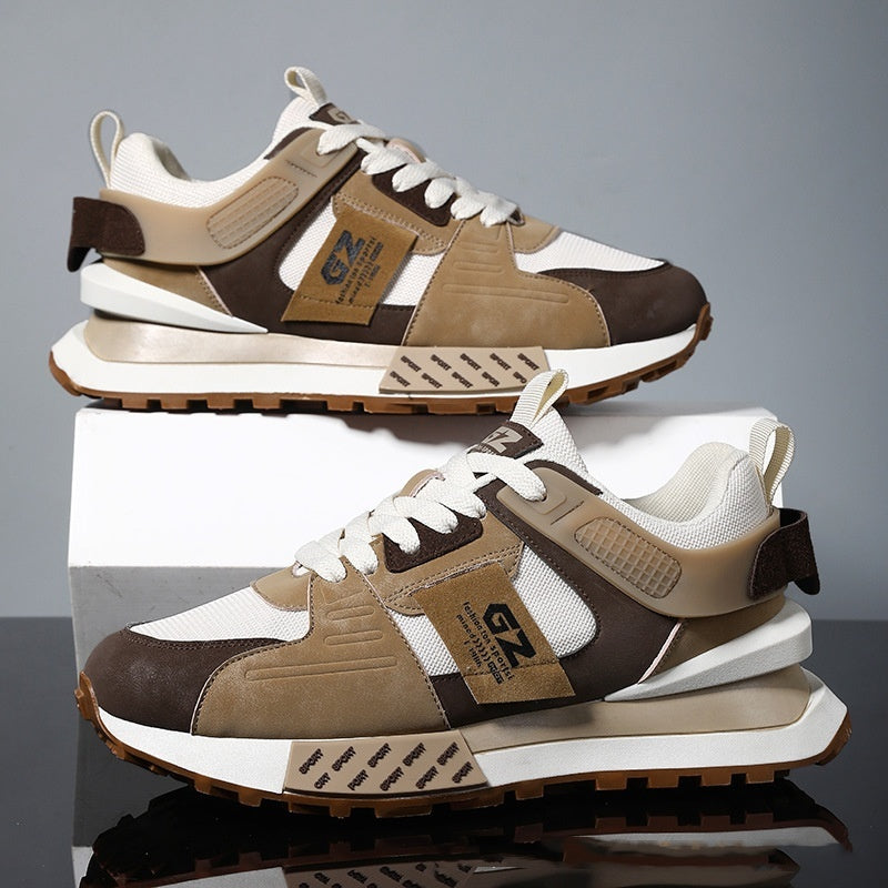 Pair of brown and beige sneakers stacked on a reflective surface with a gray background