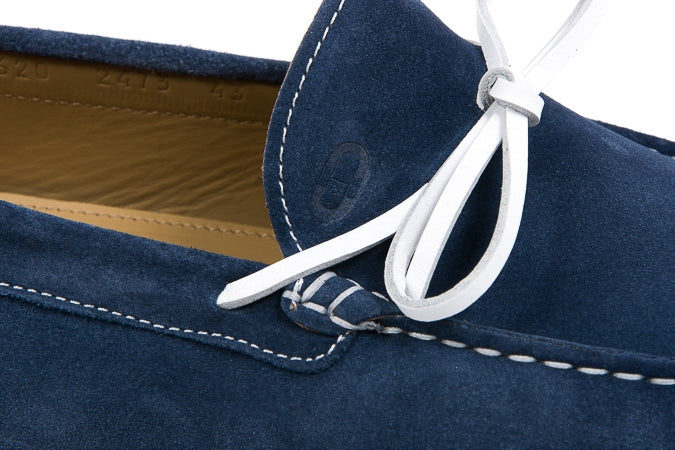 Close-up of a blue suede shoe with white laces on a white background