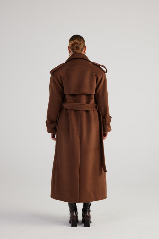 Person wearing a brown coat from behind on a white background