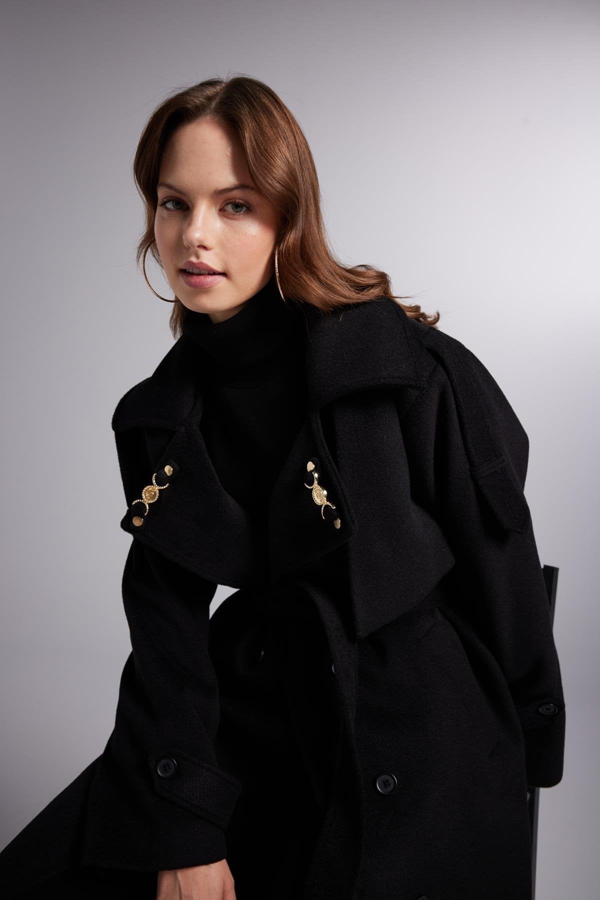 Woman wearing a black coat against a gray background